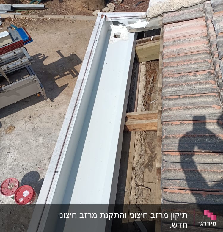מרזב לבן מותקן על גג רעפים אדומים